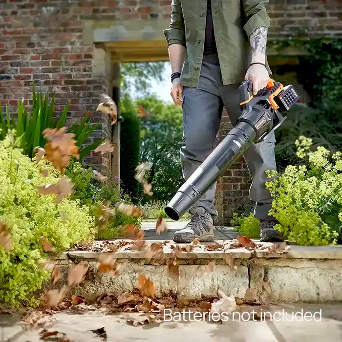 Man blowing leaves from garden path using LawnMaster 48V Axial leaf blower