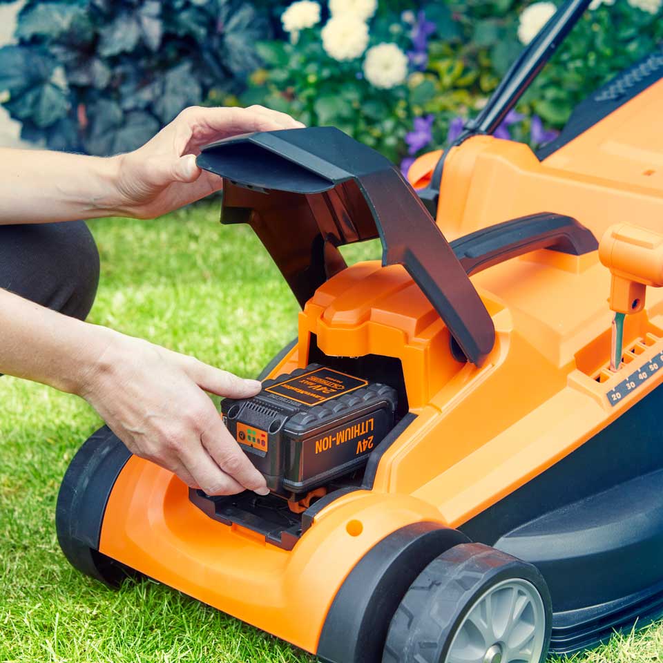 LawnMaster 24V Cordless Mower with Spare Lithium Ion Battery being inserted