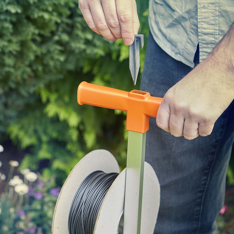 LawnMaster pegs being inserted into peg driver for robot mower
